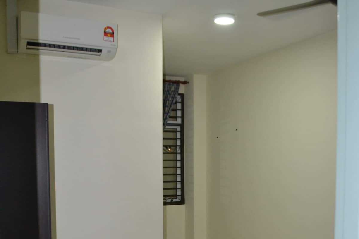 A bedroom with a bed, an air conditioner, a ceiling fan, and a door.