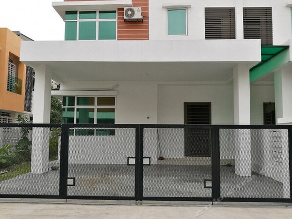 A modern two-story building with a covered entrance and a metal fence.