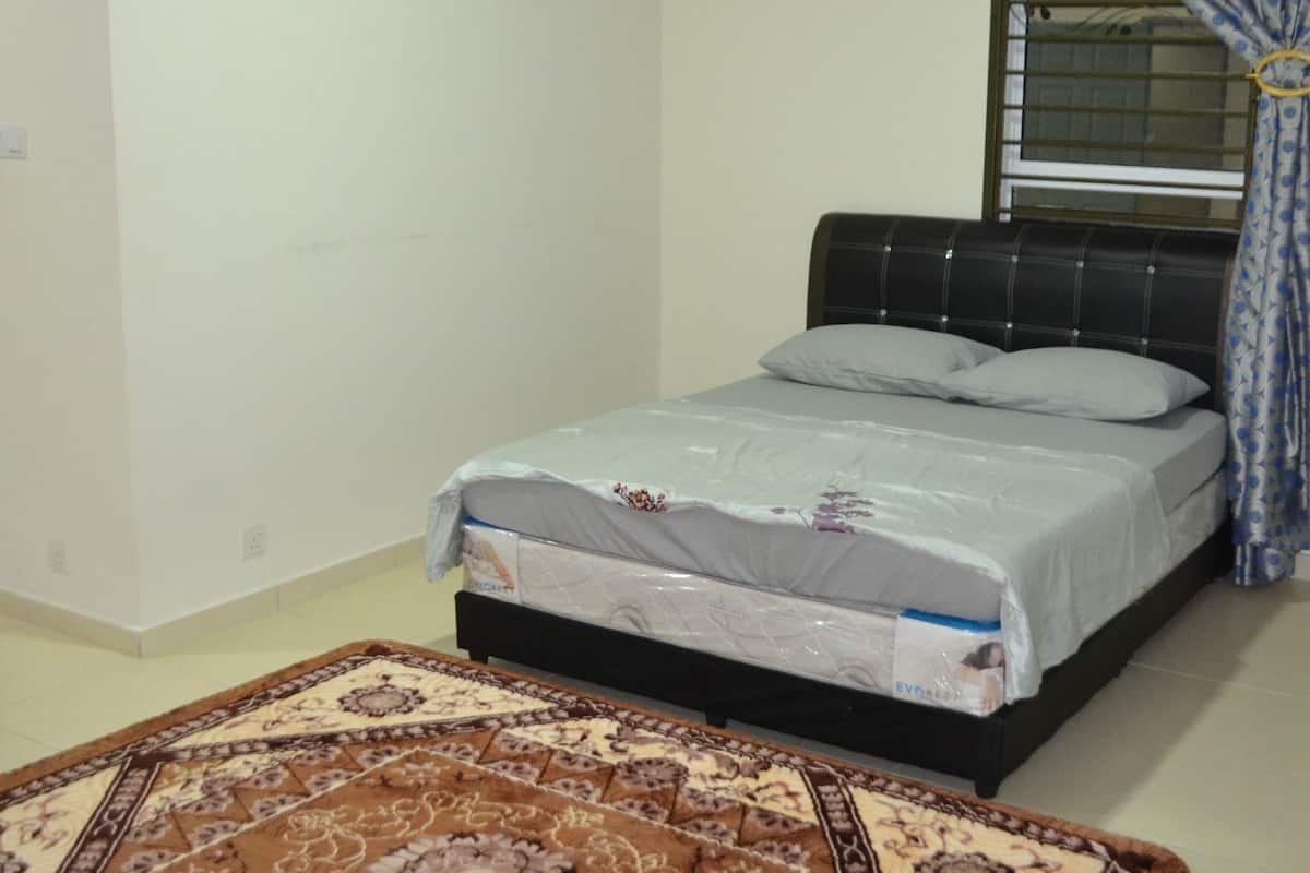 A bedroom with a bed, air conditioning unit, window with curtains, and a patterned rug.