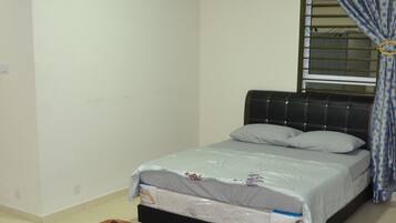 Une chambre à coucher comprenant un lit, un appareil de climatisation, une fenêtre avec des rideaux et un tapis à motifs.