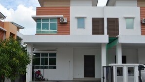A modern two-story building with a covered entrance, a bike rack, and a gated parking area. - Sitiyam Homestay Kota Warisan (Sepang)