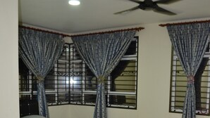 A bedroom with a bed, curtains, a ceiling fan, and a patterned rug. - Sitiyam Homestay Kota Warisan (Sepang)