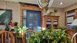 Un comedor con una mesa de madera, sillas, una planta en maceta, una puerta azul y un mueble con puertas de vidrio.