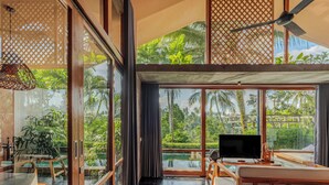A modern room with a large window, a ceiling fan, and a TV. - Amora Ubud Boutique Villas (Ubud)
