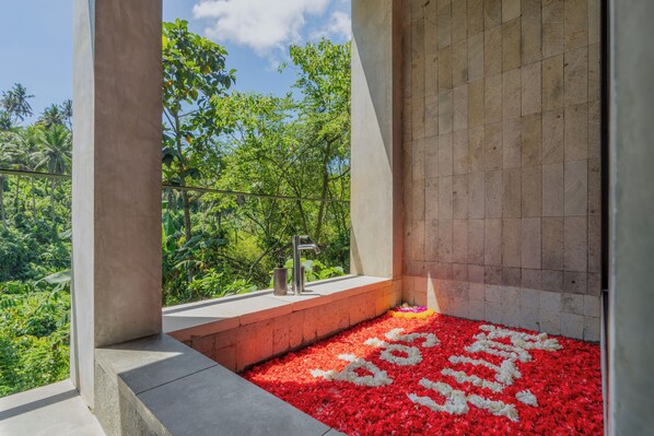 A bathroom with a concrete floor, a sink, and a view of lush greenery.