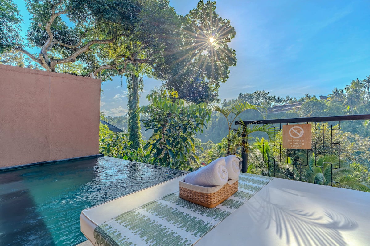 Zona de piscina con vistas a exuberante vegetación y un letrero que indica que no se permite saltar ni bucear.