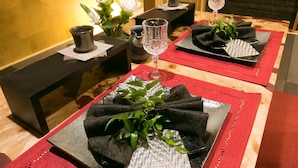 Ett matbord dukat med svarta servetter, ett glas och en vas med vita blommor.