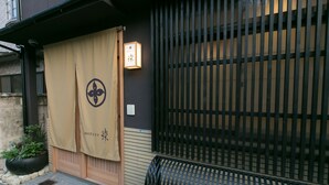En traditionell japansk byggnadsentré med en skjutdörr, en lykta och ett svart metallstaket.