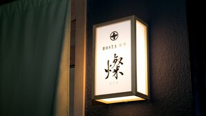 En inramad skylt med japanska tecken och namnet ”HOSTA” på en vägg.