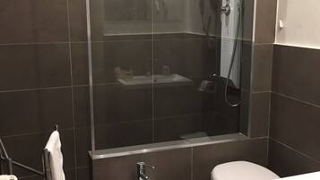 A modern bathroom with a glass-enclosed shower, a pedestal sink, and a toilet.
