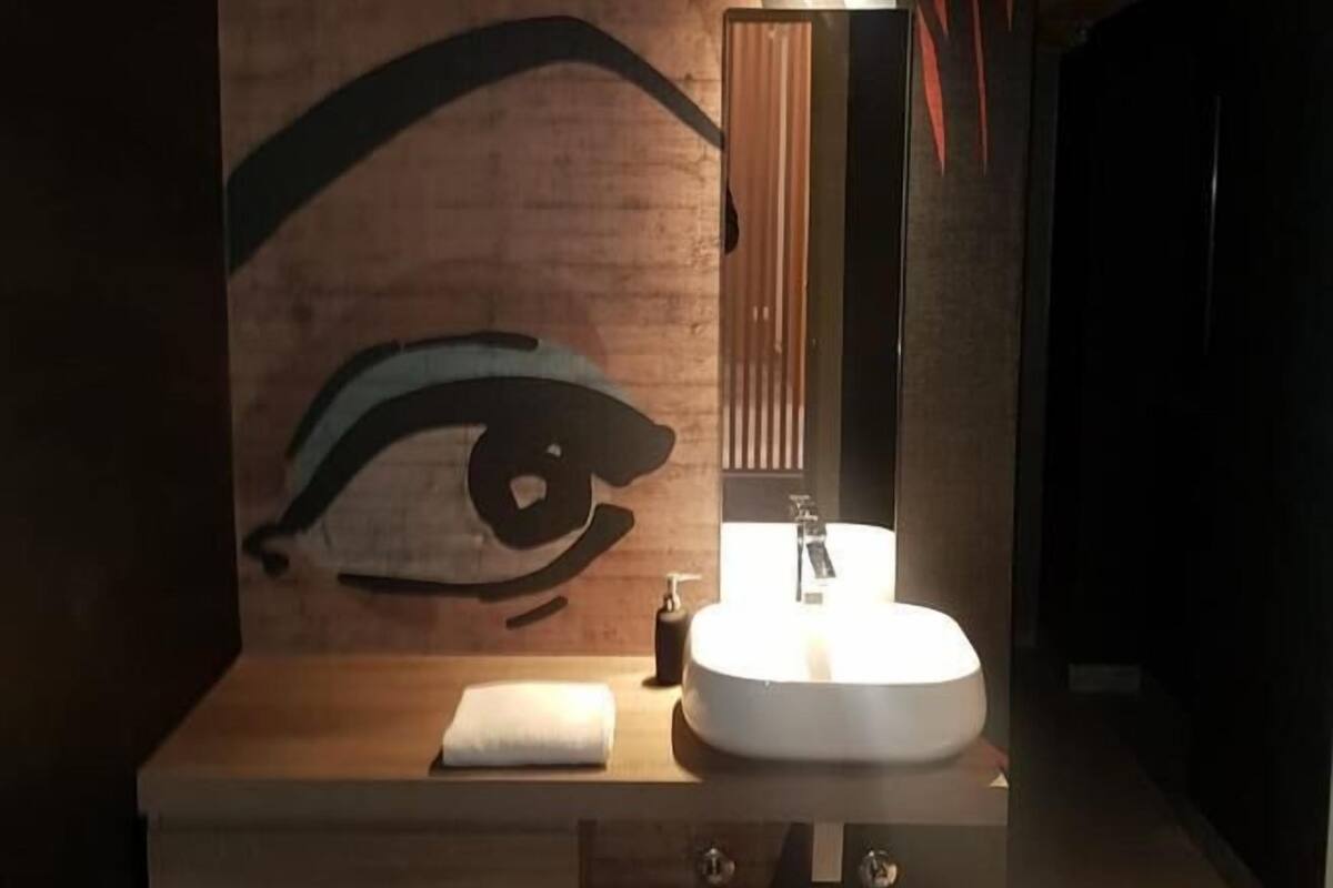 A bathroom with a large wall mural of an eye, a modern sink, and a mirror.
