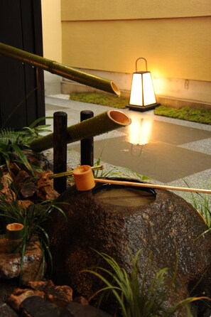 Un jardín rocoso con un farol, bambú y un pequeño estanque.