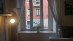 A room with a window, a potted plant, a lamp, and a wall-mounted TV. - Casa Laganà (Reggio Calabria)