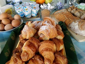 A breakfast spread with croissants, bread, eggs, and yogurt cups. - Casa Laganà (Reggio Calabria)