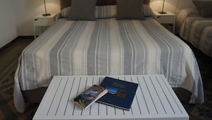 A hotel room with a large bed, two bedside tables with lamps, a small table with a book, and a patterned carpet. - Casa Laganà (Reggio Calabria)