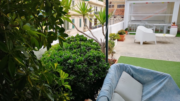 A patio area with a white chair, a small table, and potted plants. - Casa Laganà (Reggio Calabria)