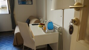 A small room with a bed, a desk with a lamp, a chair, and a radiator. - Casa Laganà (Reggio Calabria)