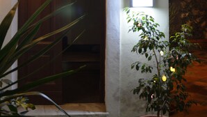 A house entrance with a wooden door, a potted plant, and string lights. - Casa Laganà (Reggio Calabria)