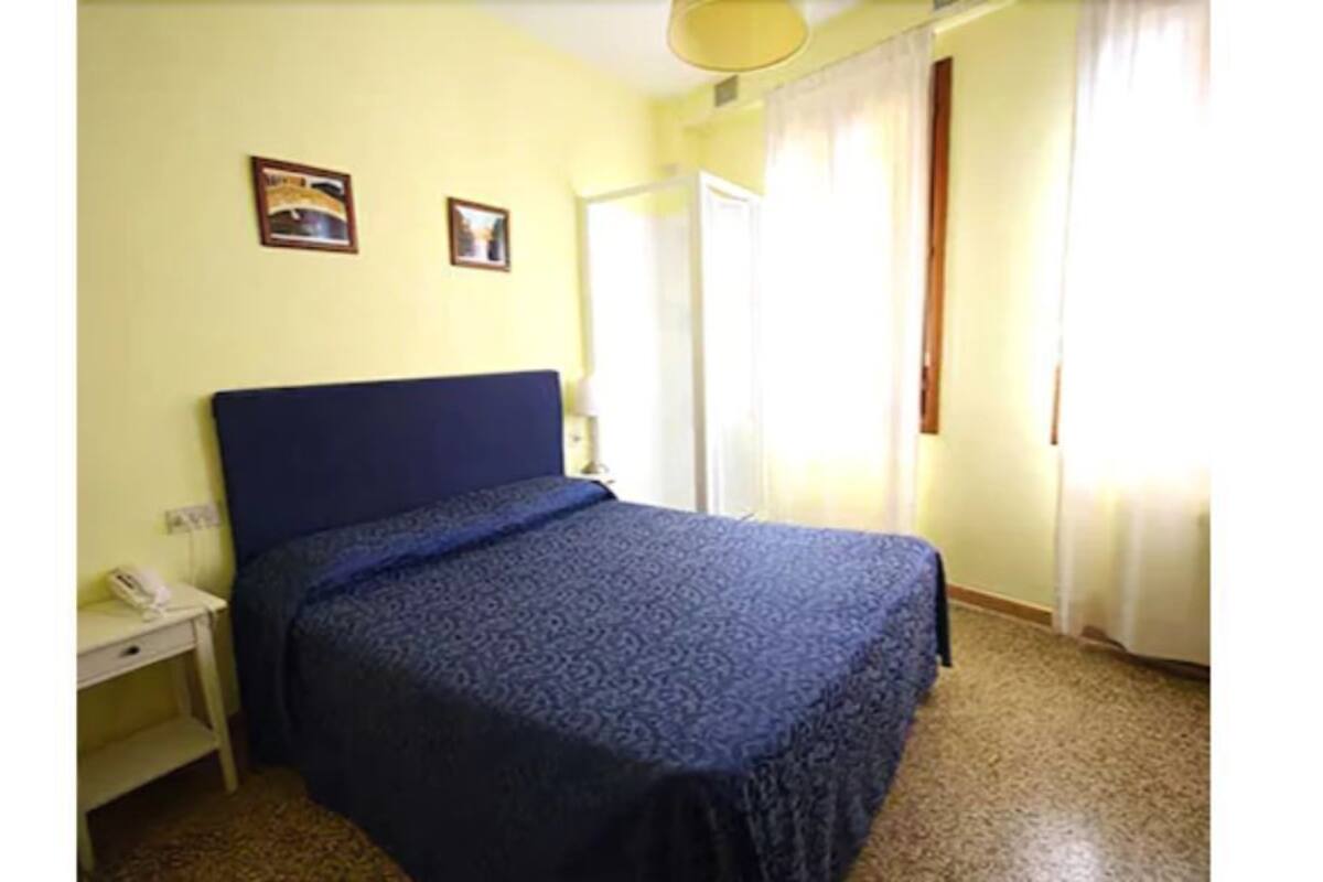 A single bed with a blue headboard in a room with a yellow wall and a white door.
