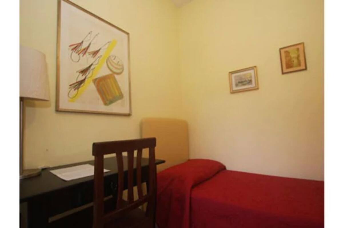 A room with a desk, chair, and a red sofa.