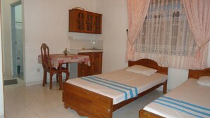 A bedroom with two wooden beds, a wooden desk, and a chair. - Tree House Holiday Home (Anuradhapura)