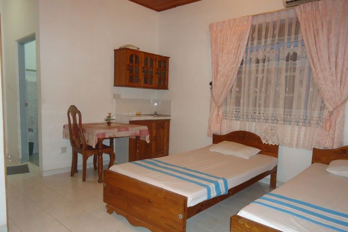 A bedroom with two wooden beds, a wooden desk, and a chair.