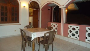 A dining area with a table and chairs, a wooden ceiling, and a pink wall with decorative cutouts. - Tree House Holiday Home (Anuradhapura)