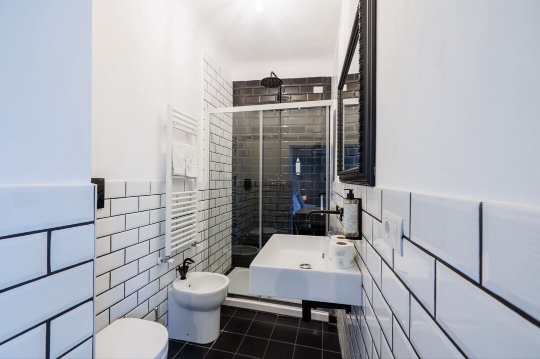 Une petite salle de bain avec des toilettes blanches, un lavabo blanc et une douche à parois de verre.