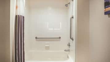 Eine Dusche mit Glastür, einer Haltestange und einer Handbrause.