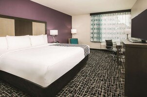 A hotel room with a large bed, a desk, a chair, and a television.