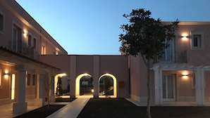 Un patio con un sendero central, arcos y un árbol.