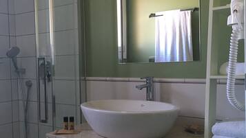 A bathroom with a glass-enclosed shower, a white sink, and a towel rack.