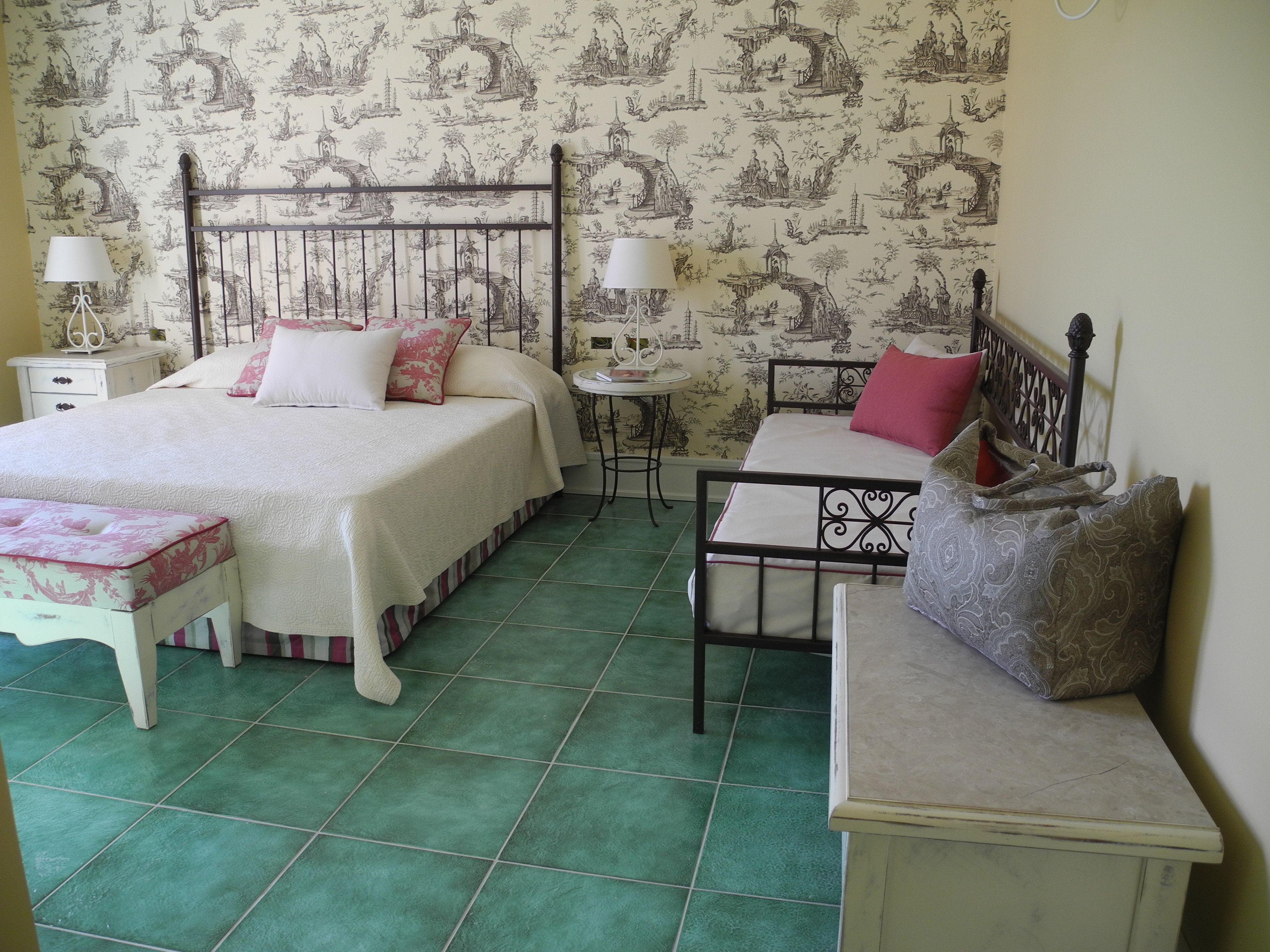 A bedroom with a bed, bedside tables, a desk, and a chair.