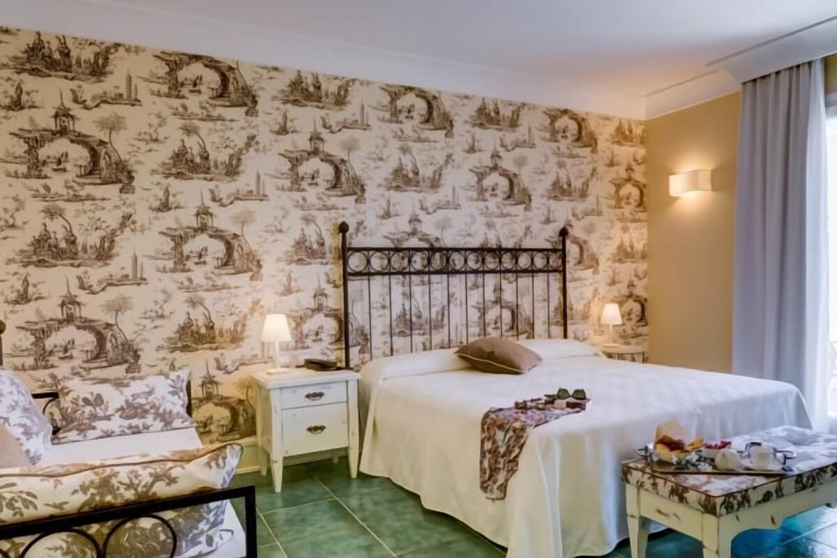 A bedroom with a bed, nightstands, a chair, and a table with a lamp.