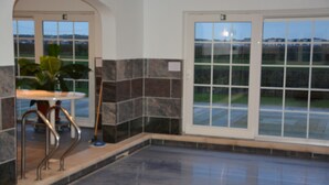 A lobby with a tiled floor, a potted plant, and a metal railing. - PS Orion (De Haan)