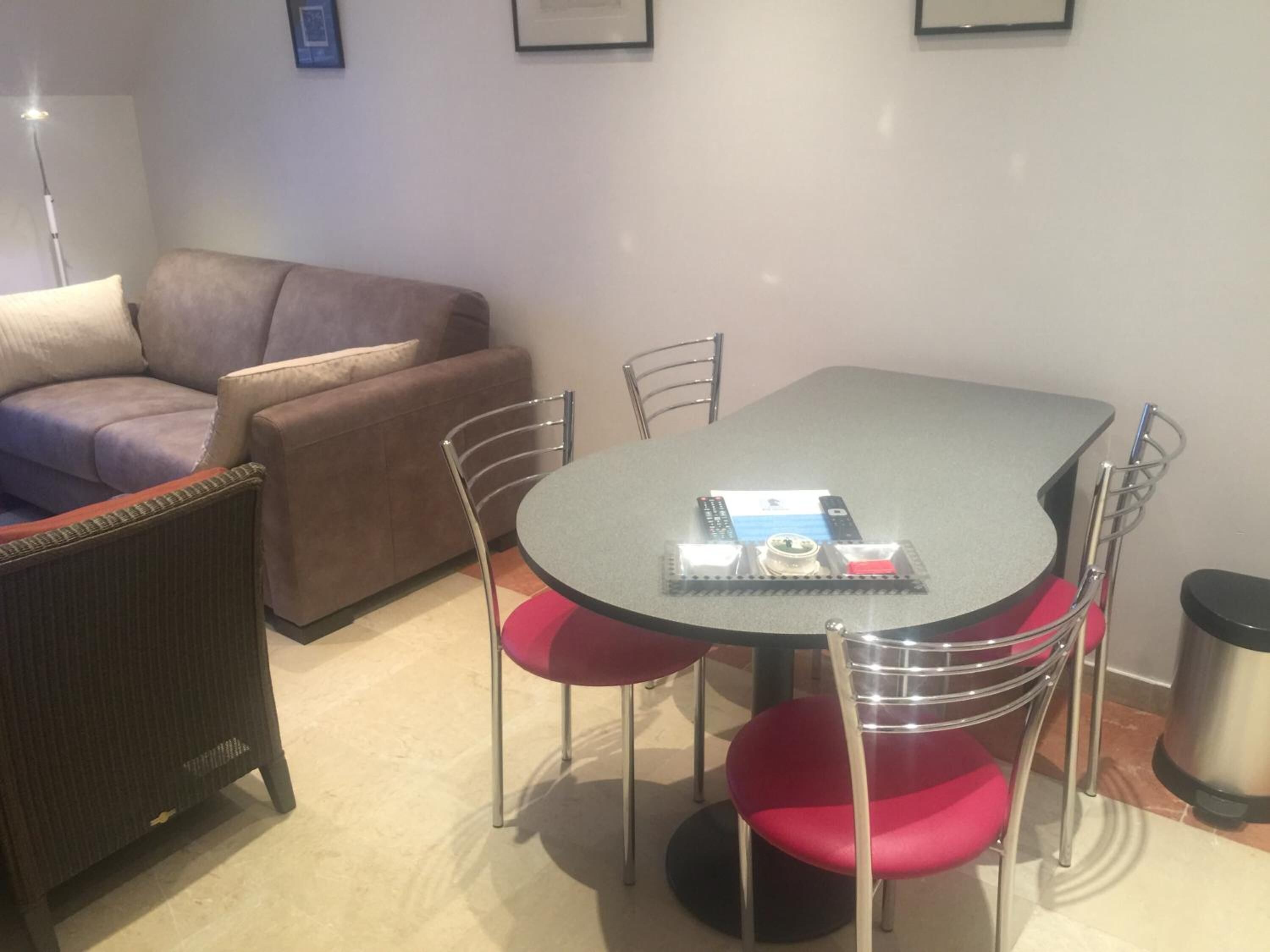 A dining area with a table and chairs, a sofa, and a trash bin.