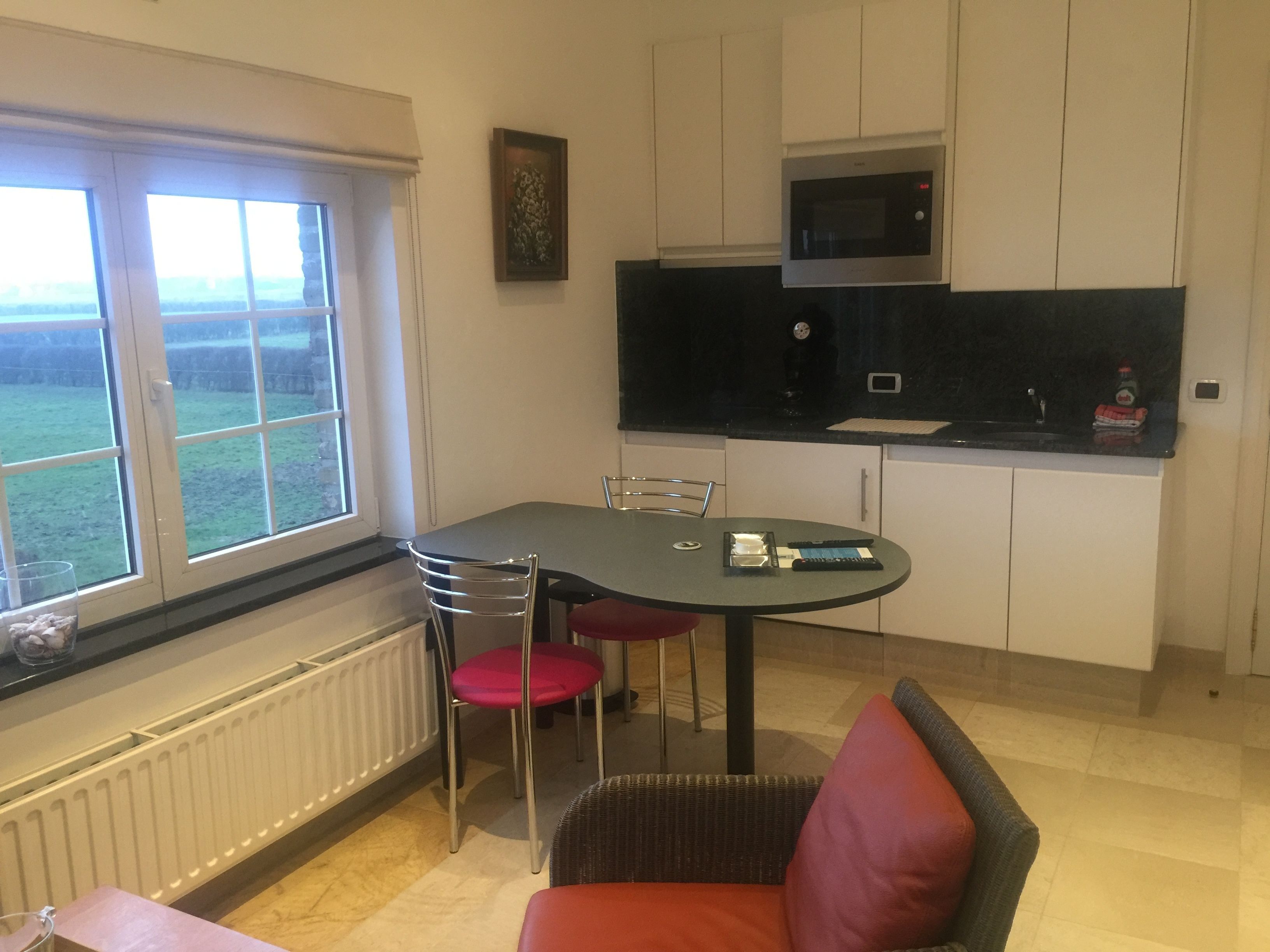 Een compact keuken met een eethoek, een raam met uitzicht en een magnetron boven het aanrecht.