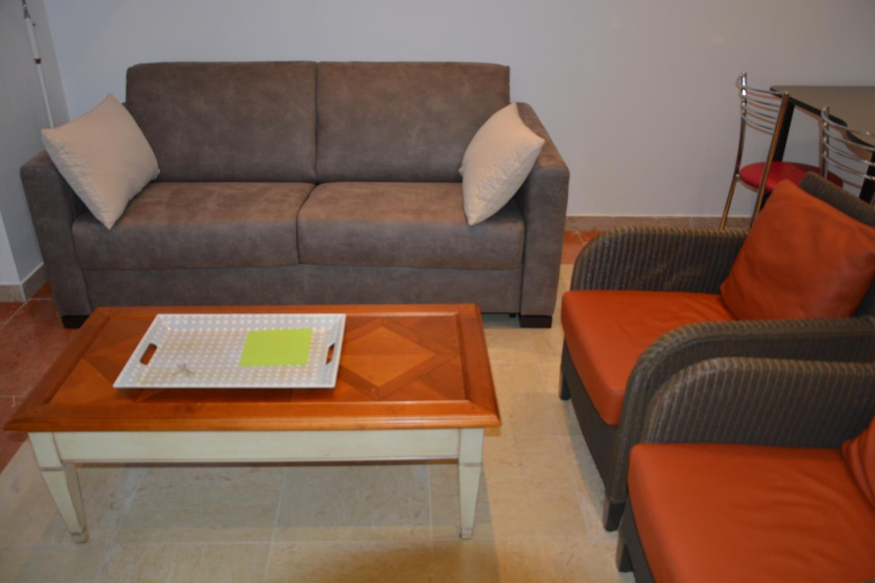 Un salon avec un canapé marron, une table basse en bois et un fauteuil orange.