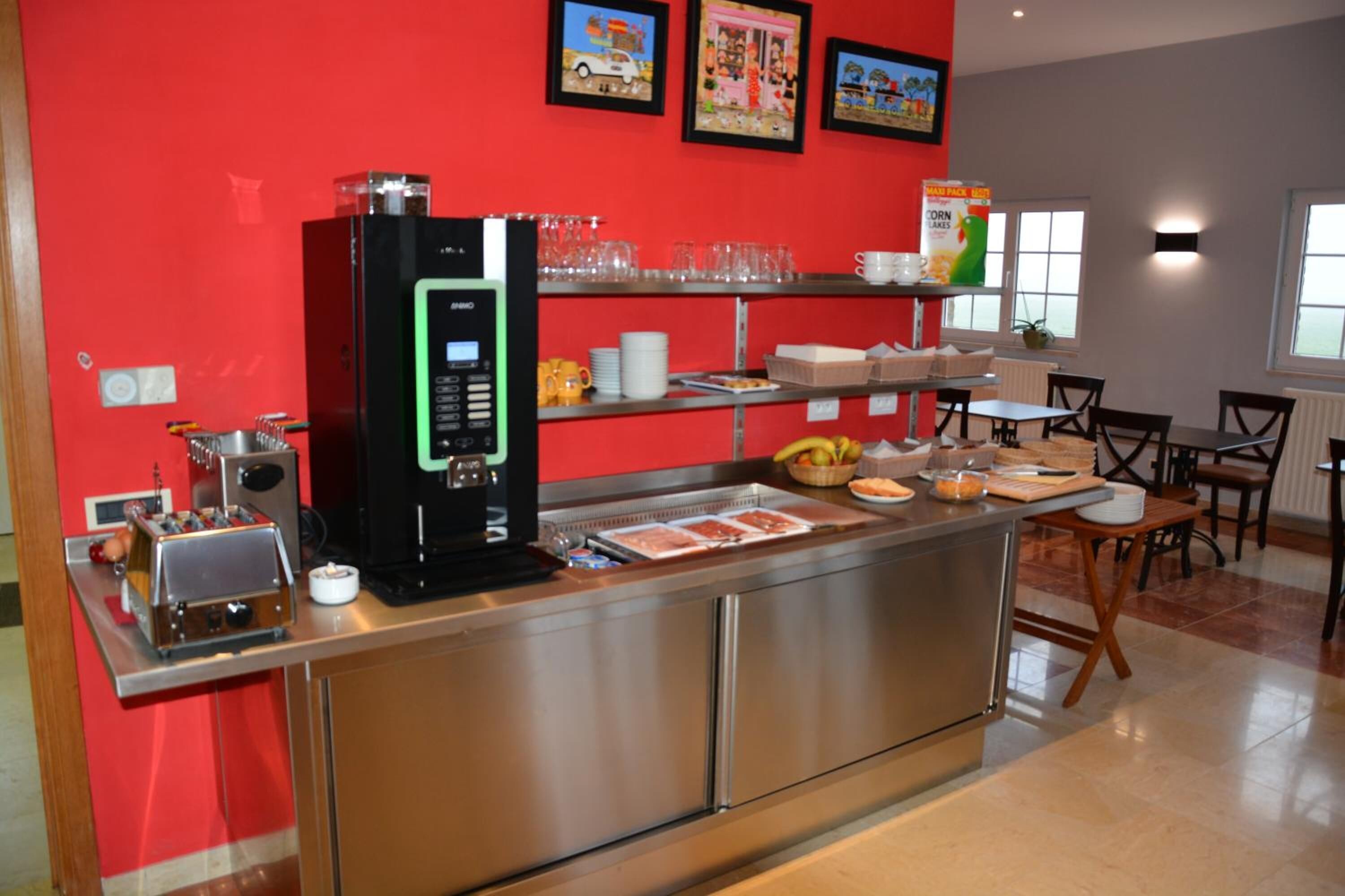 Una barra de desayuno con una máquina de café, cristalería y alimentos.