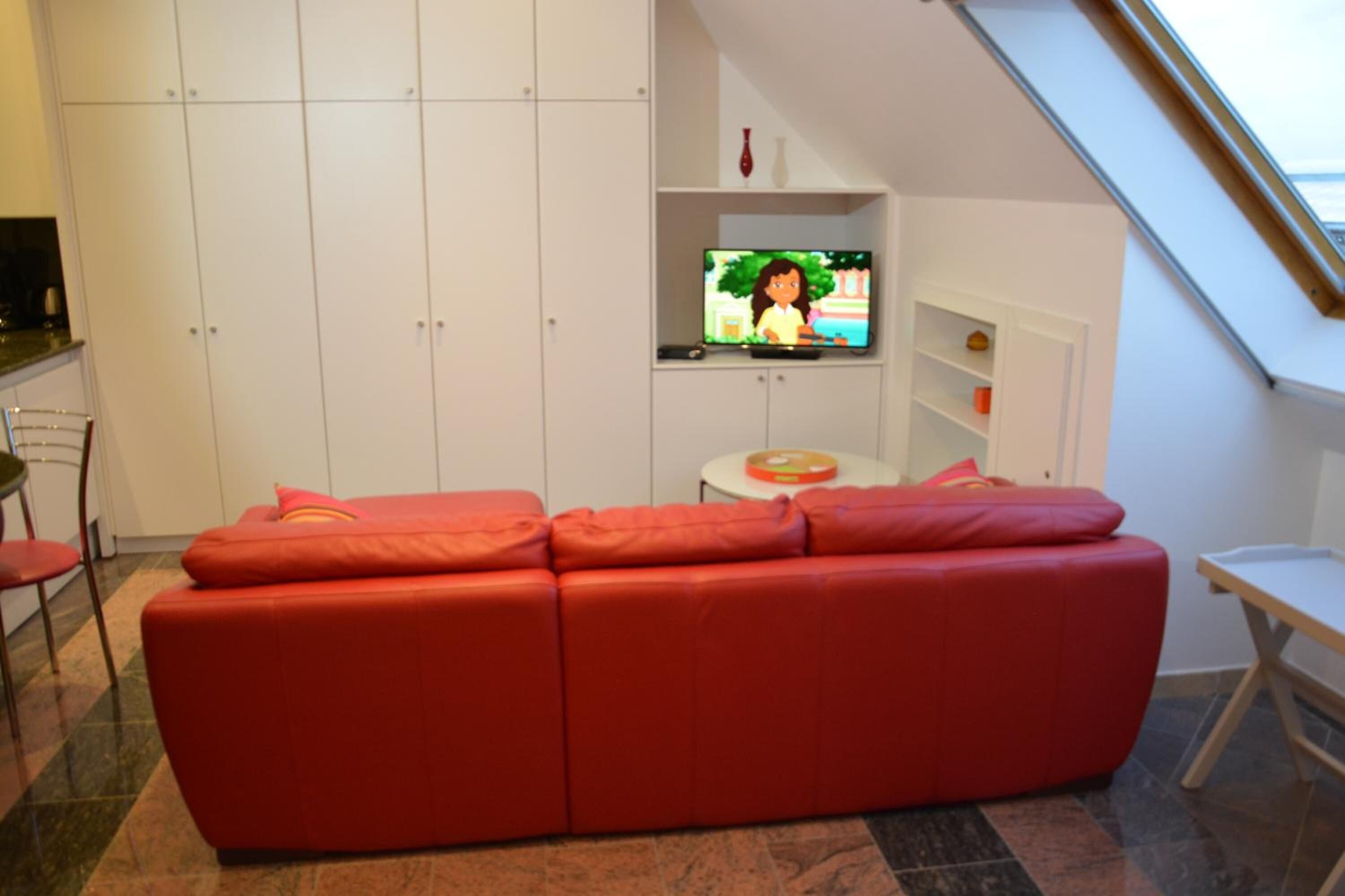 A modern living room with a red sofa, a television, and a small table.