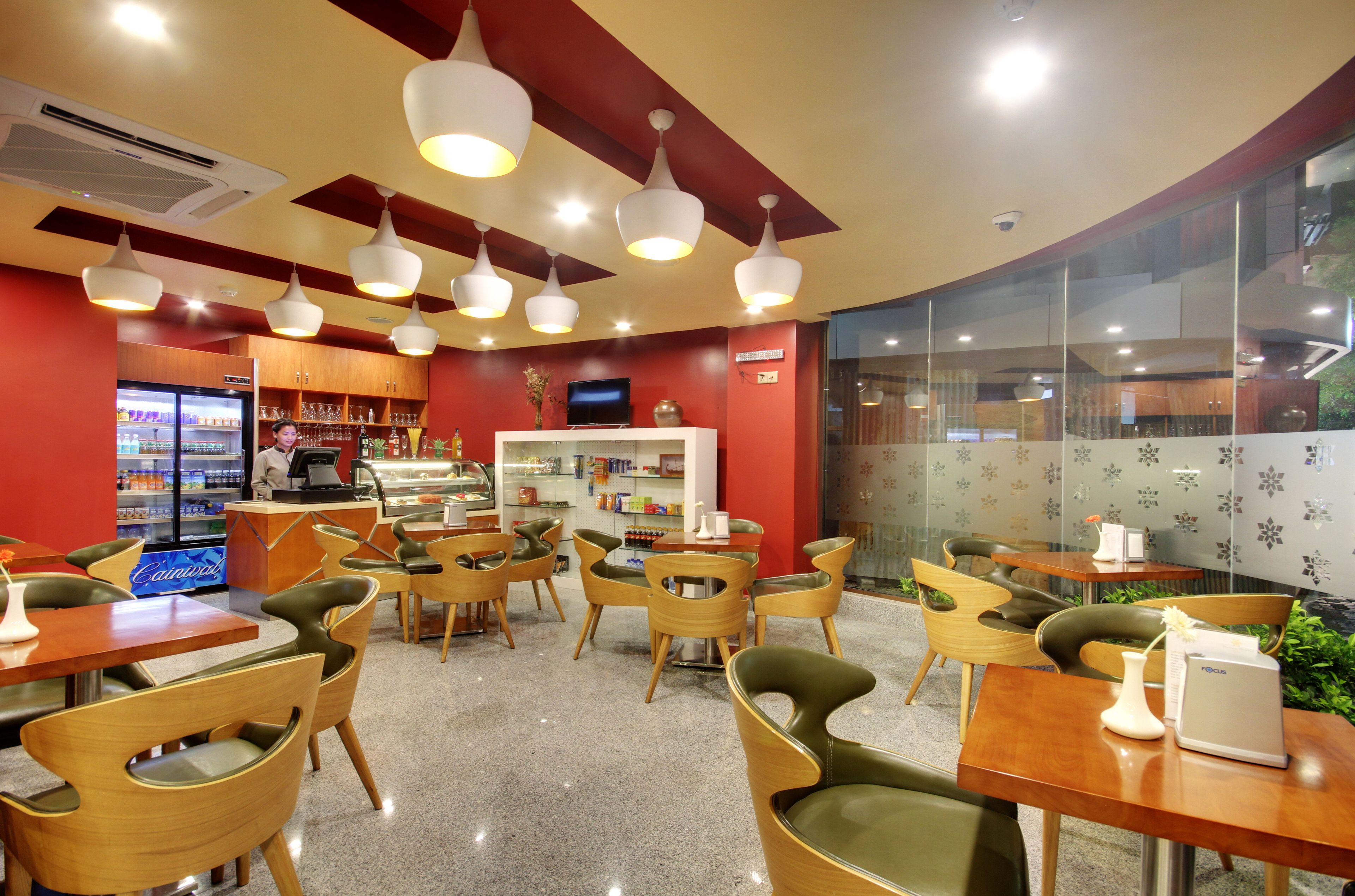 A modern cafe interior with wooden furniture, a coffee machine, and a television.