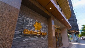 Fachada de un edificio con un letrero que dice 'China Grand' y una gran estatua dorada.