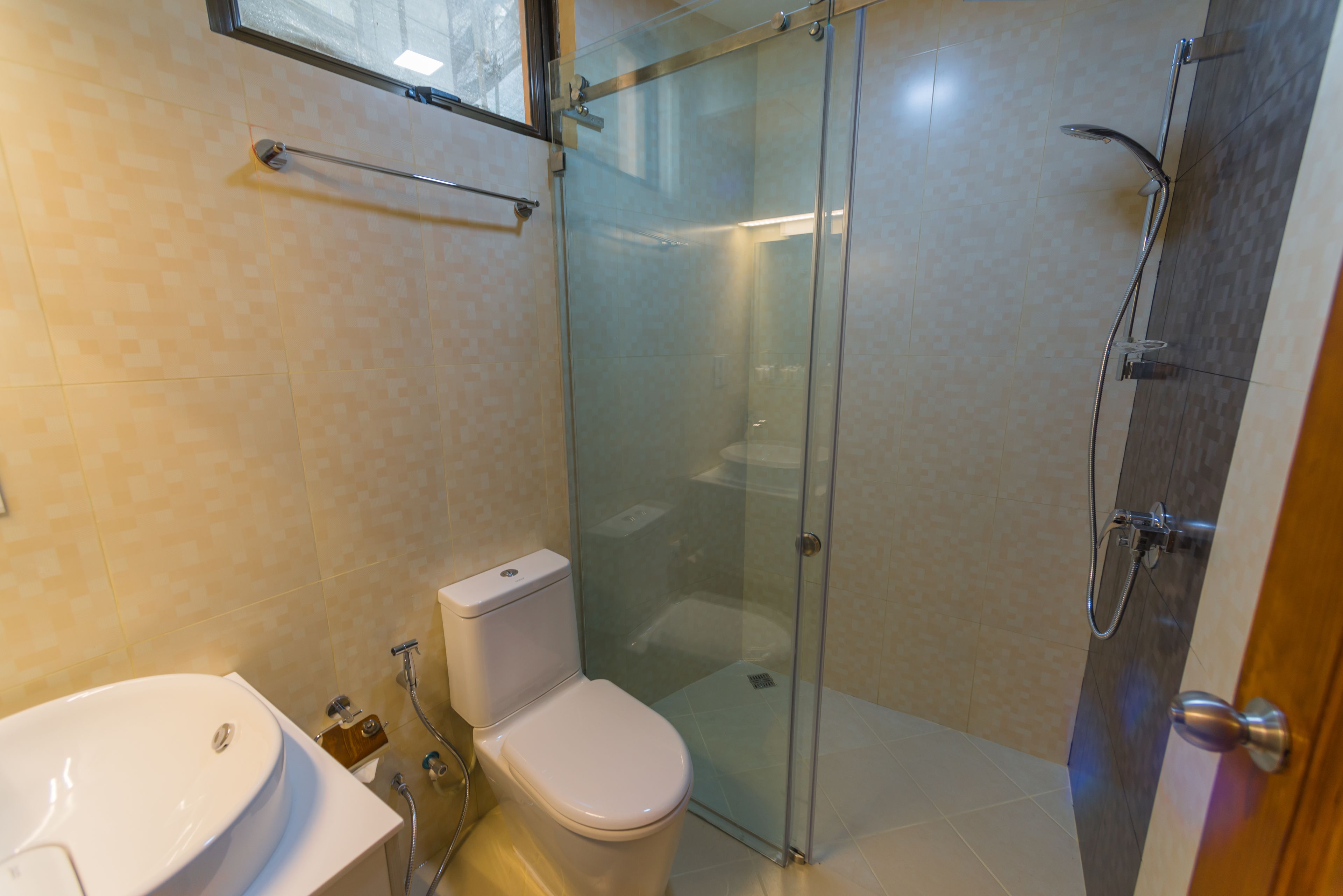 A modern bathroom with a glass-enclosed shower, a white toilet, and a sink.