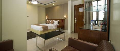 A hotel room with a bed, a glass table, a sofa, and a mirror.