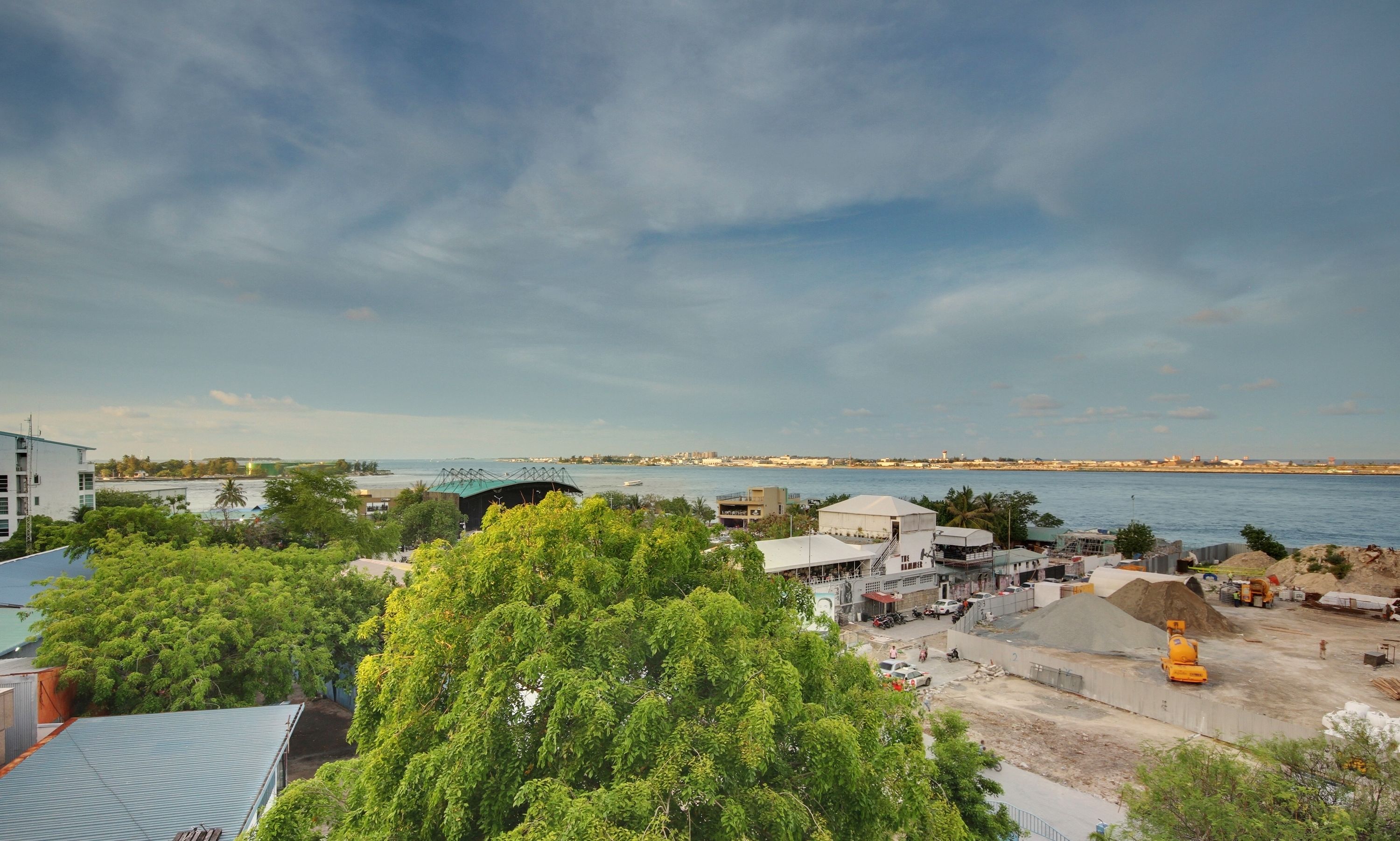 A coastal area with a view of the sea, construction site, and buildings.