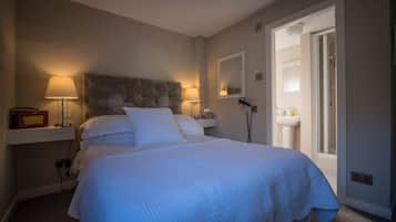 A neatly made bed with white bedding, a bedside lamp, and a telephone on a nightstand.