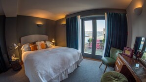 A hotel room with a large bed, a desk with a chair, and a view of the outdoors through a sliding door.