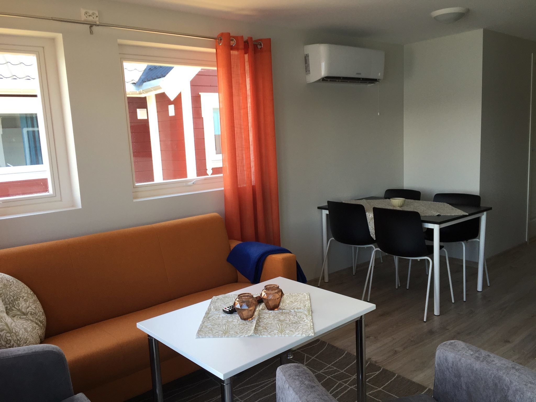 A compact living space with a sofa, a small table with a glass, and a dining area with chairs and a table.