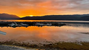 Un port de plaisance avec des bateaux amarrés, une eau calme et un coucher de soleil sur les montagnes.