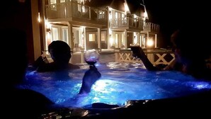 Un espace avec un jacuzzi offrant une vue sur un immeuble doté de balcons et illuminé.